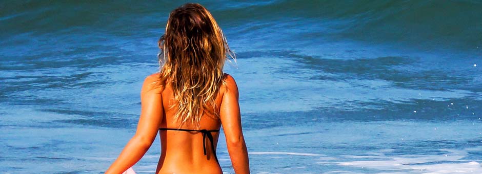 Frau mit Beach Waves am Strand vor einer Welle