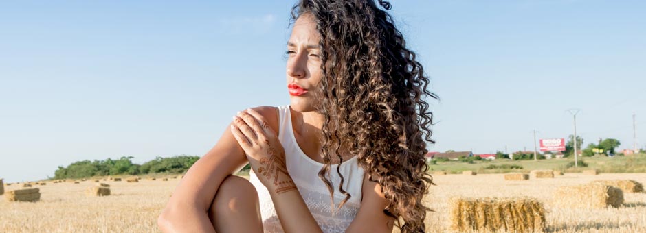 Frau mit Locken in Front von Kornfeld